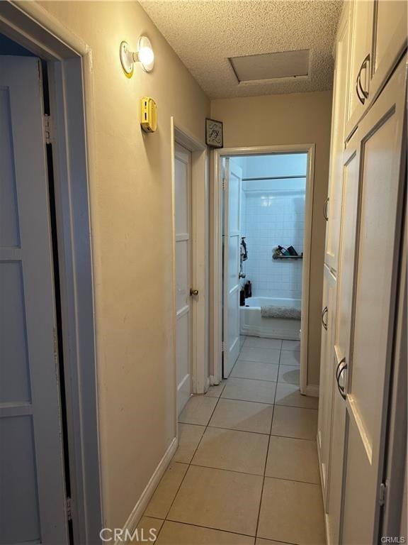 hallway with a textured ceiling and light tile patterned flooring