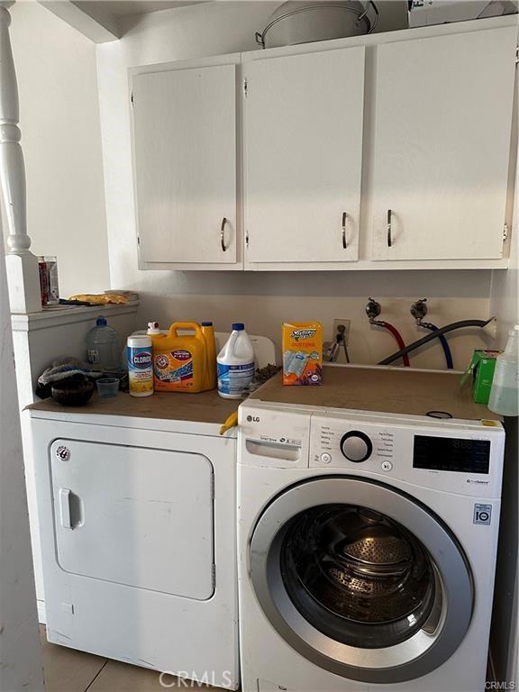 washroom featuring tile patterned floors, washing machine and dryer, and cabinets