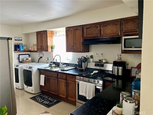 kitchen with washing machine and dryer, light tile flooring, appliances with stainless steel finishes, dark brown cabinets, and sink