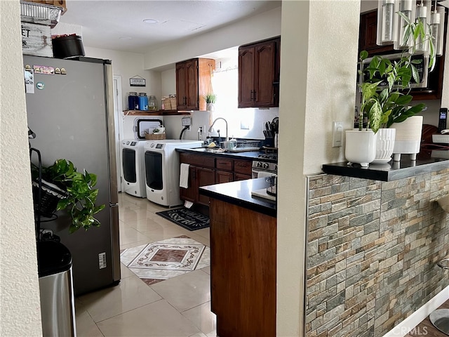 kitchen featuring washing machine and dryer, light tile floors, and stainless steel fridge