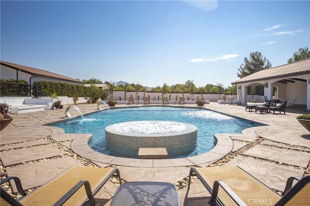 view of swimming pool featuring a hot tub, pool water feature, and a patio area