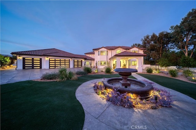 mediterranean / spanish house featuring a garage and a yard