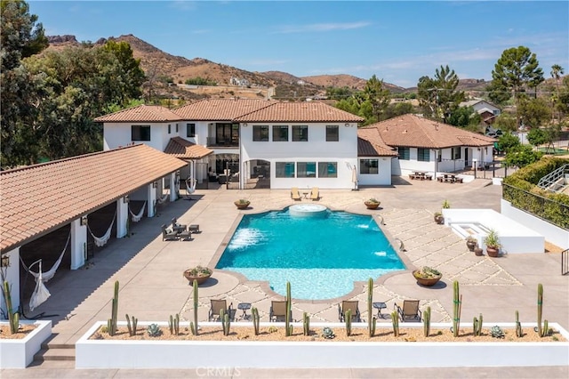 view of pool featuring pool water feature, a mountain view, and a patio area