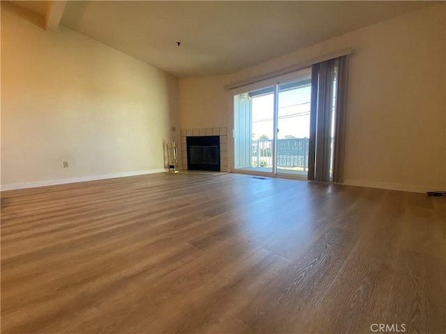 unfurnished living room with hardwood / wood-style floors and a tile fireplace