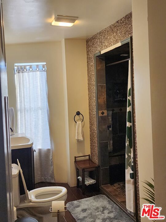 bathroom with tiled shower, vanity, and toilet