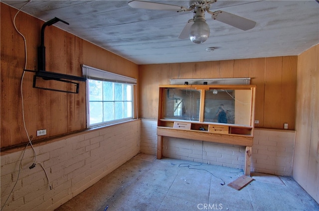 interior space with wood walls and ceiling fan