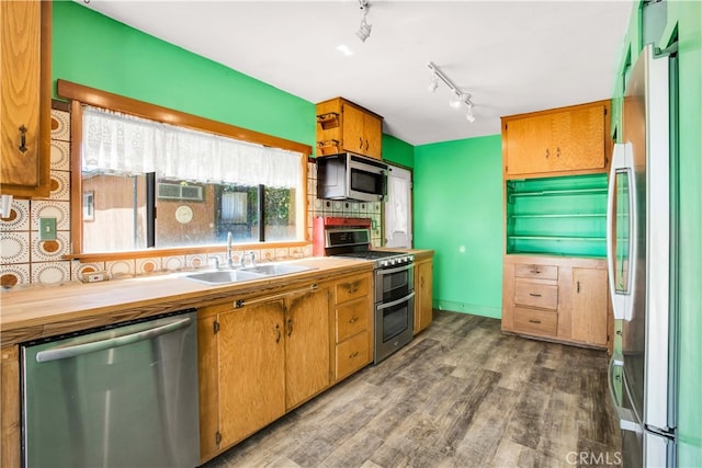 kitchen featuring appliances with stainless steel finishes, hardwood / wood-style flooring, tasteful backsplash, sink, and track lighting