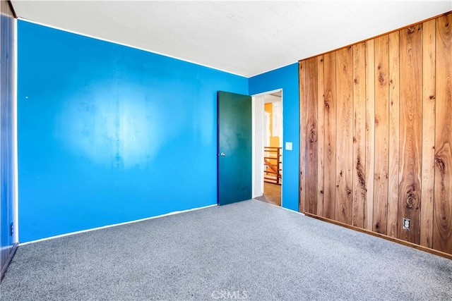 carpeted empty room with wooden walls