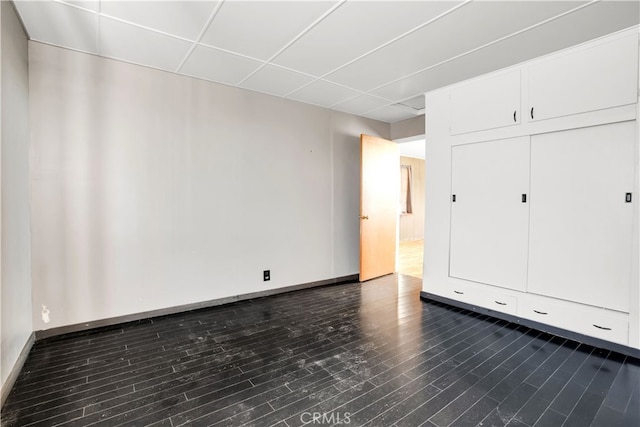 empty room featuring a paneled ceiling and dark wood-type flooring