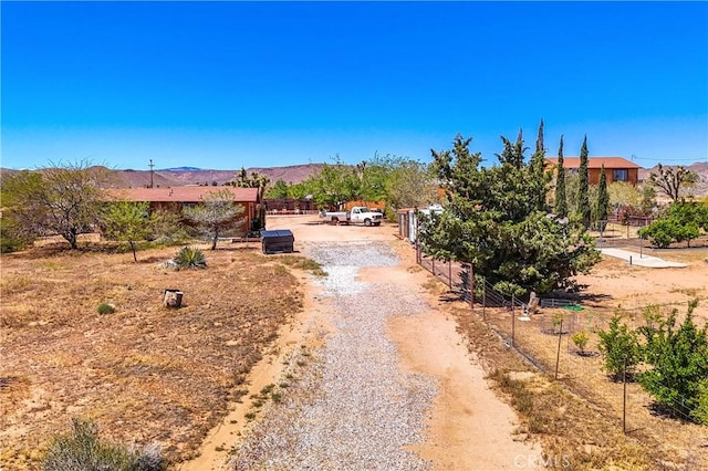 view of street featuring a mountain view and gravel driveway