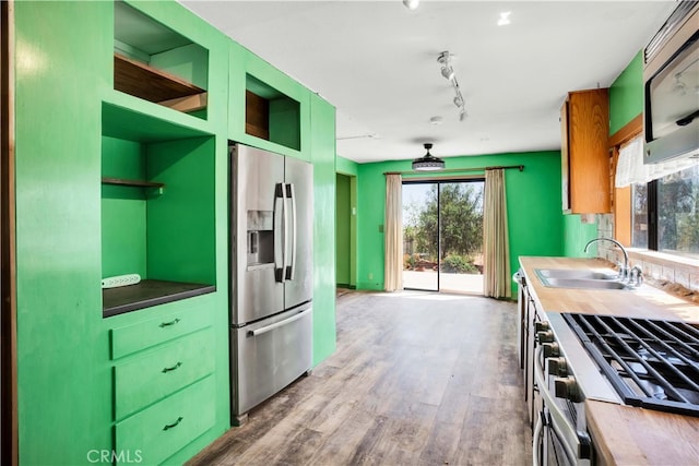 kitchen featuring stainless steel appliances, track lighting, wood counters, sink, and hardwood / wood-style flooring