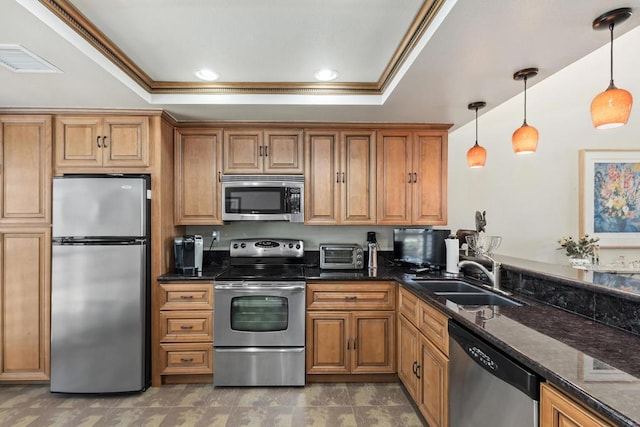 kitchen with appliances with stainless steel finishes, dark stone counters, a raised ceiling, sink, and decorative light fixtures