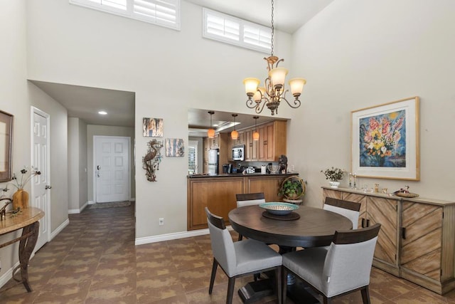 dining room with a towering ceiling, plenty of natural light, and a notable chandelier