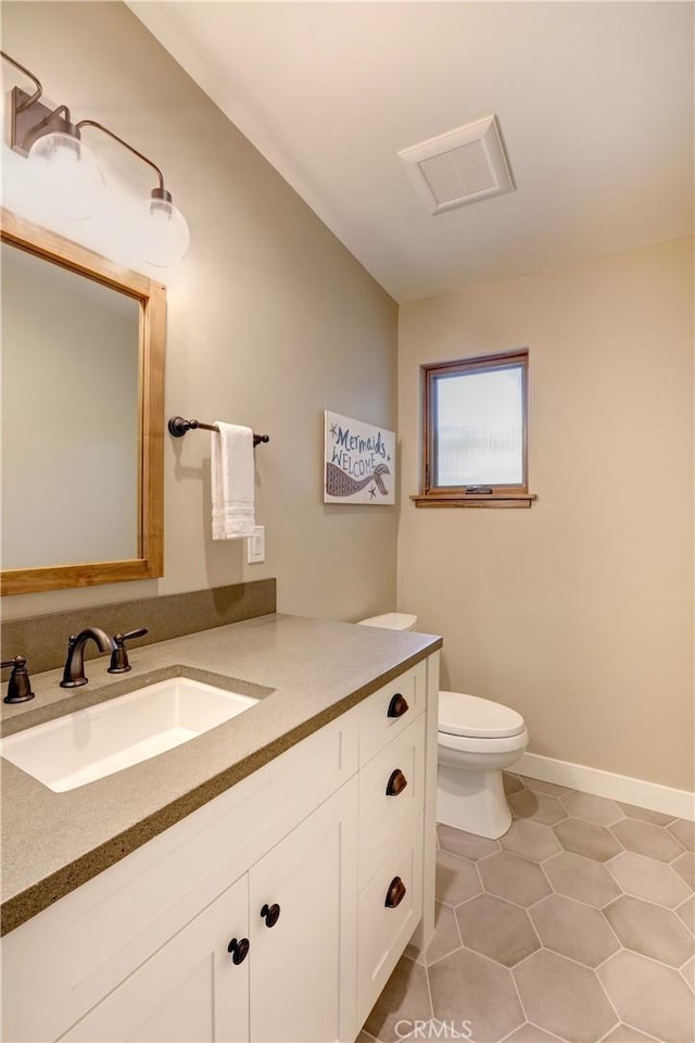 bathroom with toilet, vanity, and tile patterned flooring