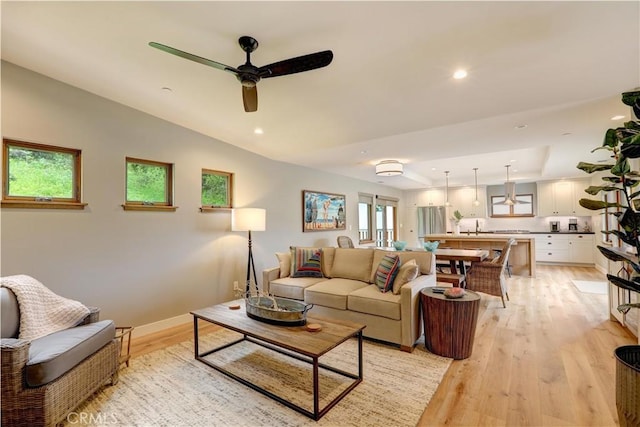 living room with ceiling fan, a healthy amount of sunlight, light wood-type flooring, and sink