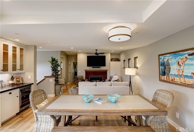 dining room featuring ceiling fan, light hardwood / wood-style flooring, and wine cooler