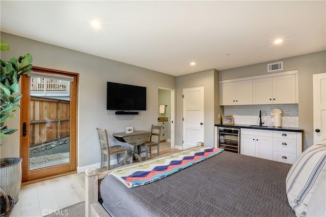 bedroom featuring wine cooler, sink, and light hardwood / wood-style flooring