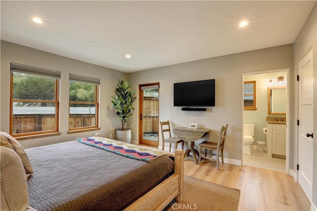 bedroom with sink, ensuite bathroom, and light wood-type flooring