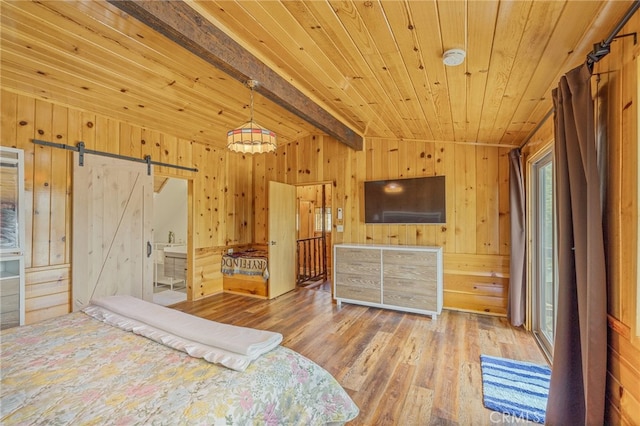 bedroom with a barn door, wood walls, lofted ceiling with beams, and hardwood / wood-style flooring