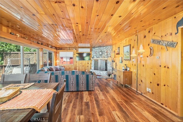 dining room featuring wood ceiling, a stone fireplace, wood walls, and dark wood-type flooring