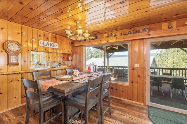 dining room with wood walls, a water view, wood-type flooring, and a chandelier