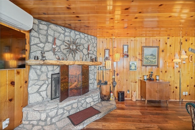 living room with a stone fireplace, wood walls, a wall mounted air conditioner, and hardwood / wood-style flooring