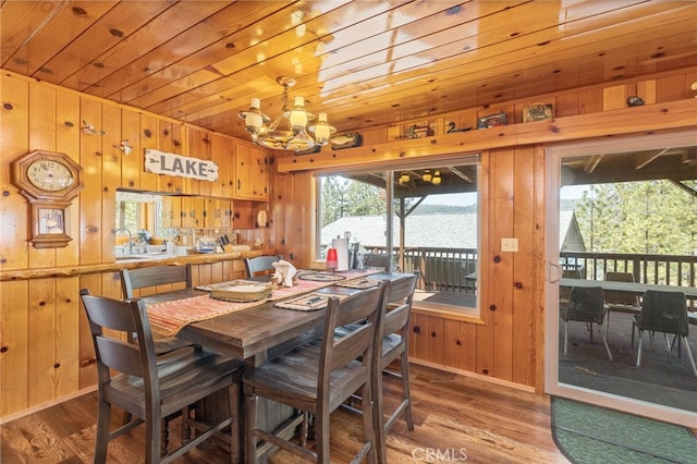 dining area with wooden walls, hardwood / wood-style floors, a water view, and a chandelier