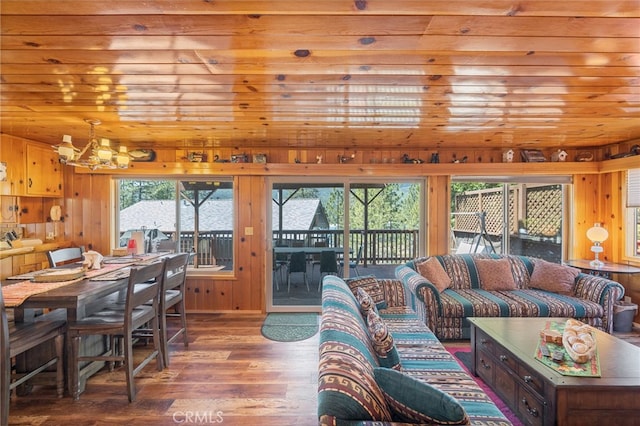 living room with wood-type flooring, wooden walls, wooden ceiling, and a notable chandelier