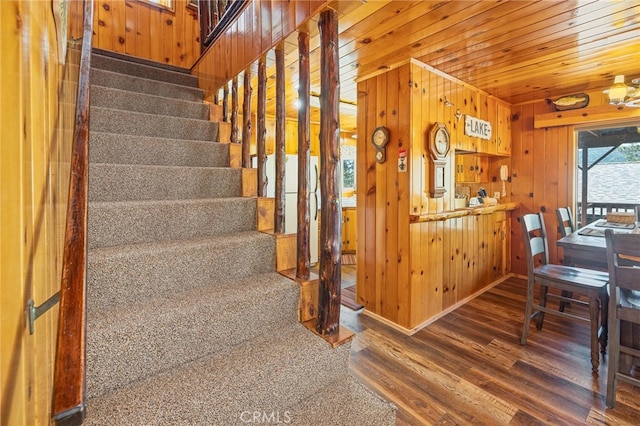 stairway featuring hardwood / wood-style floors, wooden ceiling, and wooden walls