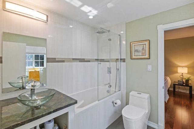 full bathroom featuring combined bath / shower with glass door, sink, wood-type flooring, and toilet