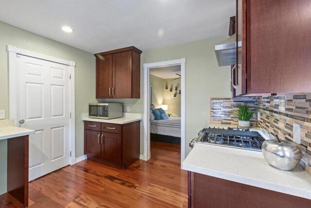 kitchen with decorative backsplash, dark hardwood / wood-style flooring, and stove