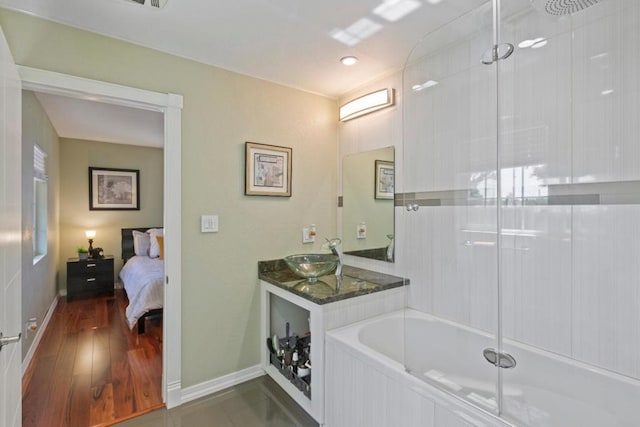 bathroom with vanity, hardwood / wood-style flooring, and a relaxing tiled tub