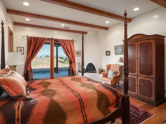 bedroom featuring beamed ceiling, wood-type flooring, and access to exterior