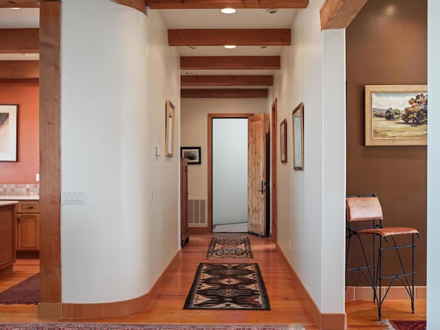 hallway featuring beam ceiling and light hardwood / wood-style floors