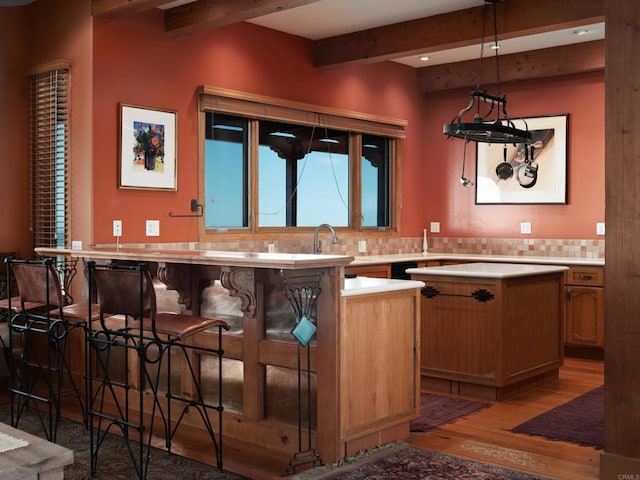 bar with hardwood / wood-style floors, beam ceiling, tasteful backsplash, and pendant lighting