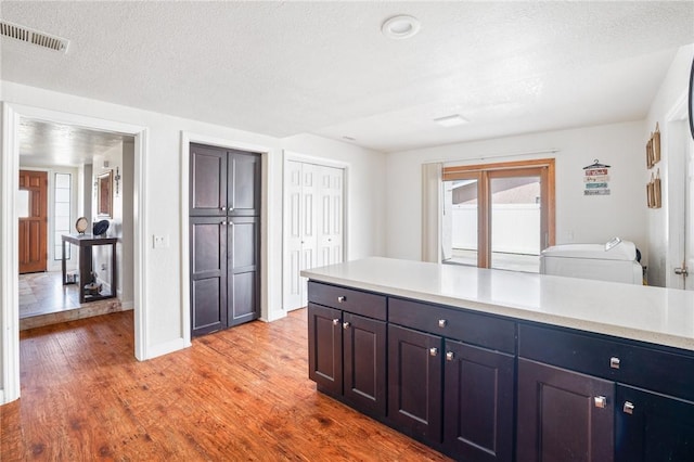 kitchen featuring independent washer and dryer, a textured ceiling, and light hardwood / wood-style flooring