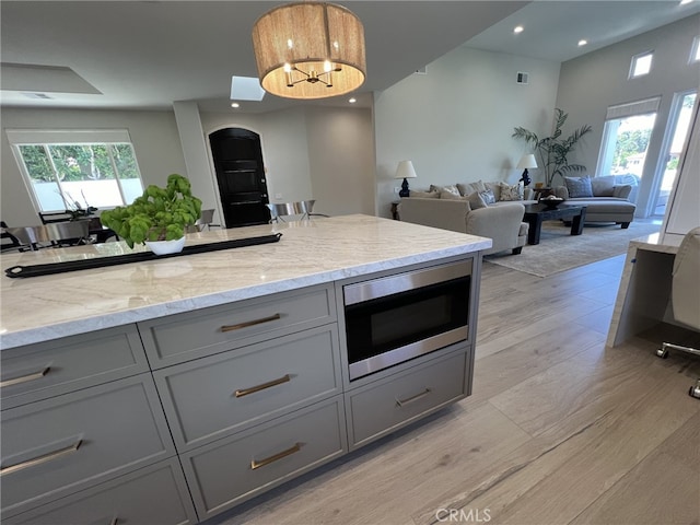 kitchen with light stone counters, a wealth of natural light, gray cabinets, and built in microwave