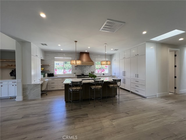 kitchen featuring a breakfast bar area, white cabinetry, pendant lighting, and a skylight