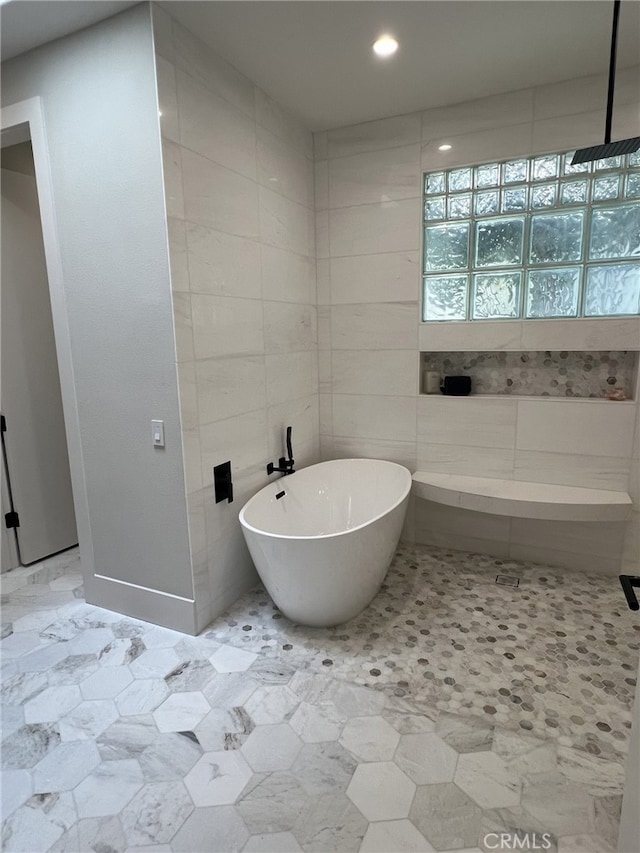 bathroom featuring tile walls and a tub to relax in