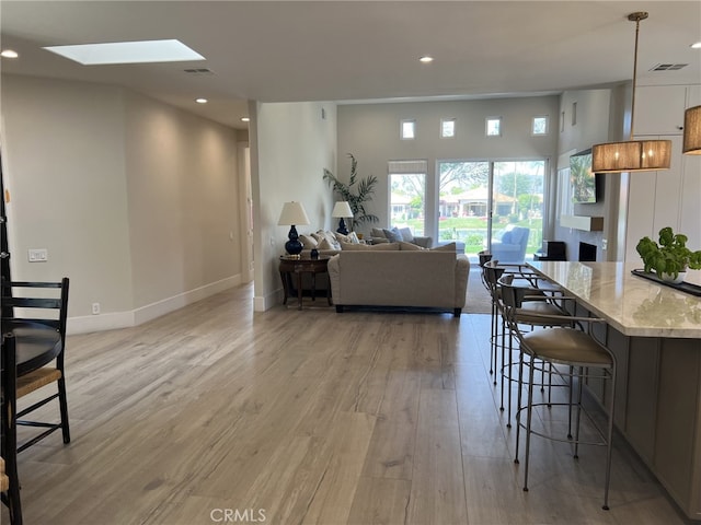 living room with light wood-type flooring and a skylight