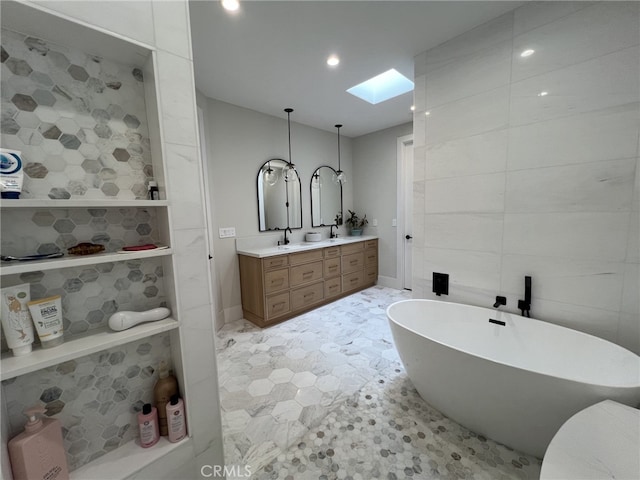 bathroom with vanity, a skylight, tile walls, and a washtub