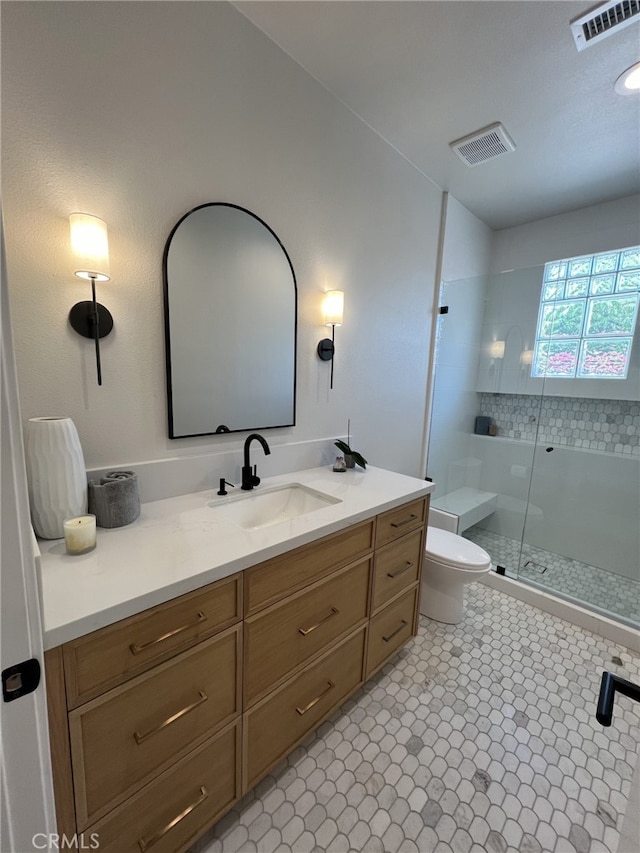 bathroom featuring toilet, vanity, and a shower with shower door