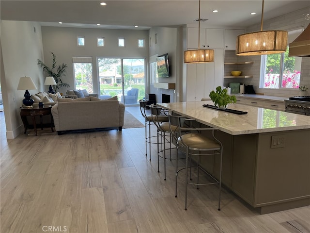 kitchen with light stone countertops, decorative light fixtures, white cabinetry, tasteful backsplash, and a large island