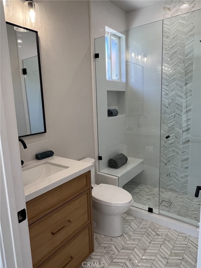 bathroom featuring tile patterned floors, toilet, vanity, and walk in shower