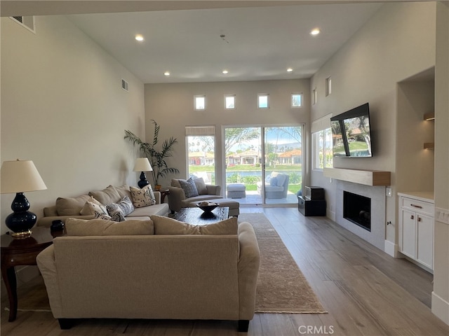 living room featuring light wood-type flooring and a towering ceiling