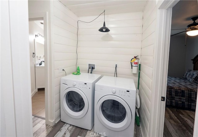 washroom featuring wood-type flooring, washer and clothes dryer, wooden walls, and ceiling fan