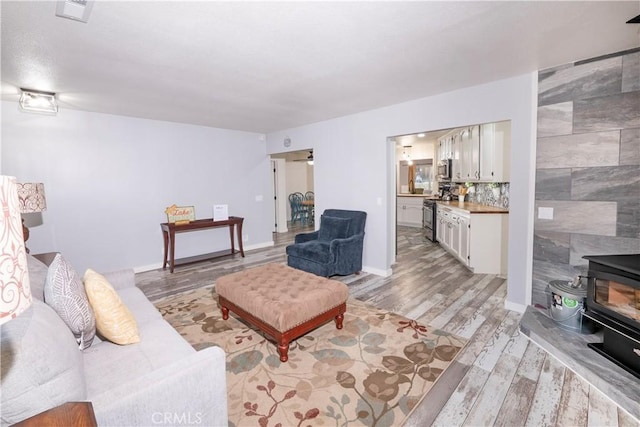 living room featuring light hardwood / wood-style floors, a wood stove, and tile walls