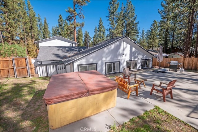 rear view of property featuring a patio and a hot tub