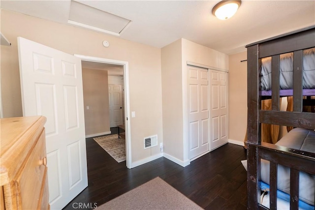 bedroom with dark hardwood / wood-style flooring and a closet