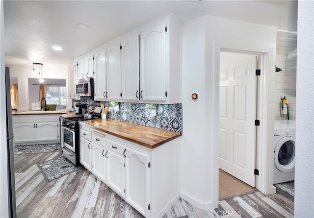 kitchen with white cabinetry, butcher block countertops, washer / clothes dryer, appliances with stainless steel finishes, and light wood-type flooring